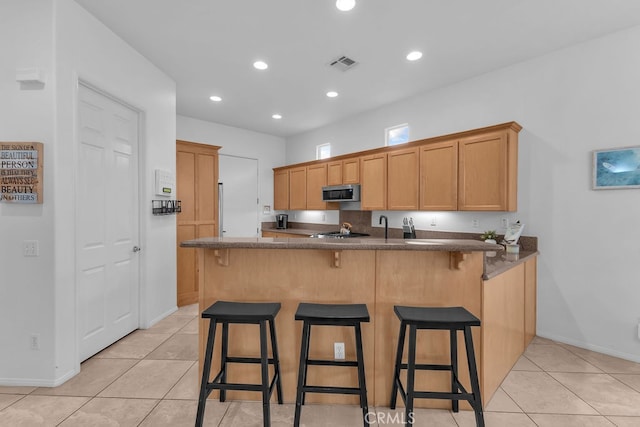82689 Odlum Dr, Indio, CA 92201 - kitchen featuring stainless steel microwave, a peninsula, light tile patterned floors, and visible vents