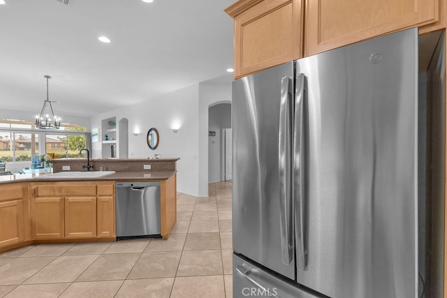 82689 Odlum Dr, Indio, CA 92201 - kitchen with light tile patterned floors, hanging light fixtures, a sink, arched walkways, and appliances with stainless steel finishes