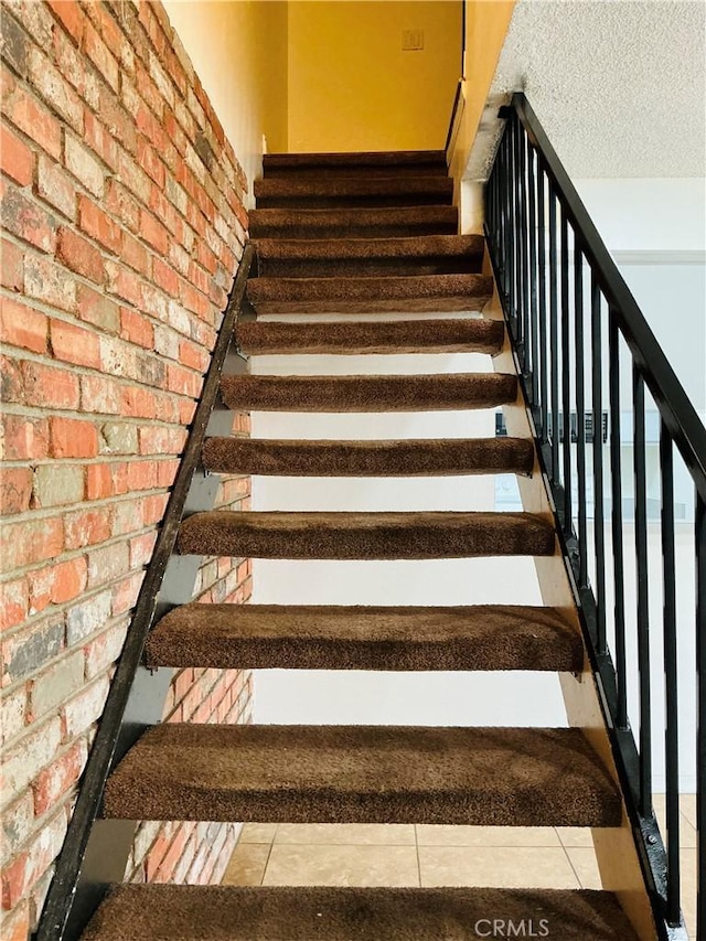 3545 20th St, Highland, CA 92346 - stairs with brick wall, a textured ceiling, and tile patterned flooring