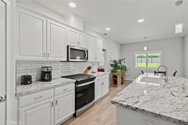 kitchen featuring tasteful backsplash, visible vents, appliances with stainless steel finishes, and a sink