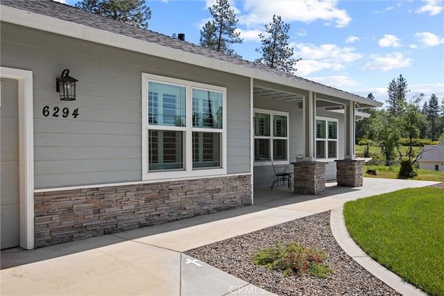 exterior space featuring stone siding and a patio