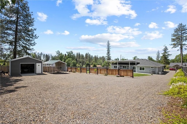 view of yard featuring gravel driveway, fence, an outbuilding, and a garage
