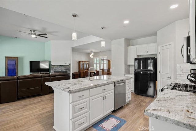 kitchen with light wood-type flooring, stainless steel appliances, a sink, and tasteful backsplash
