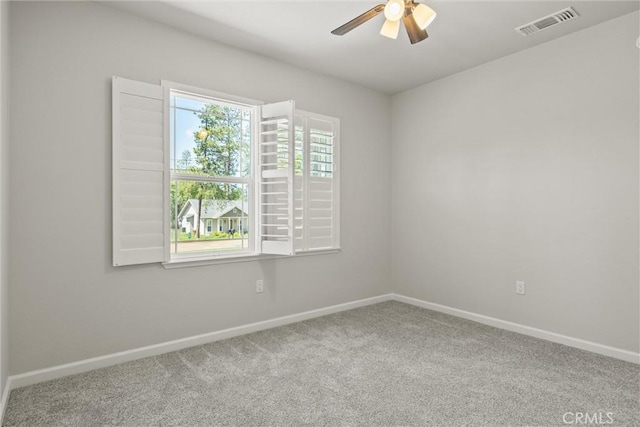 carpeted spare room featuring baseboards, a ceiling fan, and visible vents