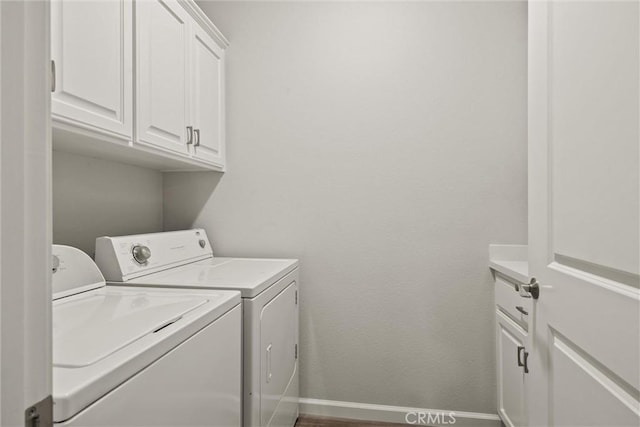 clothes washing area with washing machine and clothes dryer, cabinet space, and baseboards