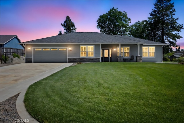 single story home with an attached garage, a front lawn, driveway, and stone siding