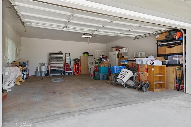 garage with a garage door opener and freestanding refrigerator