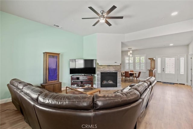 living room featuring baseboards, a ceiling fan, visible vents, and light wood-style floors