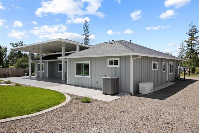 rear view of house with fence, roof with shingles, board and batten siding, and cooling unit