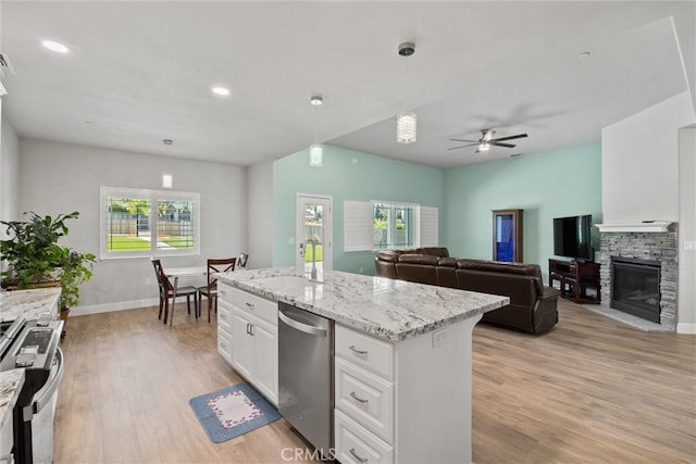 6294 W Wagstaff Rd, Paradise, CA 95969 - kitchen featuring stainless steel appliances, a stone fireplace, a ceiling fan, white cabinets, and light wood-style flooring