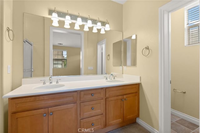 bathroom with double vanity, tile patterned floors, baseboards, and a sink