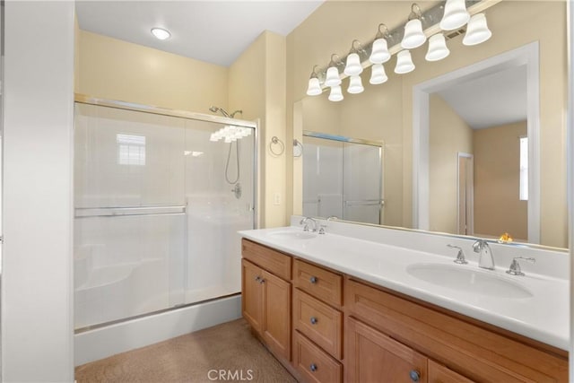 bathroom with double vanity, a shower stall, and a sink