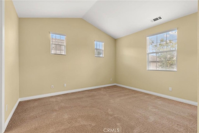 carpeted empty room featuring vaulted ceiling, visible vents, and baseboards