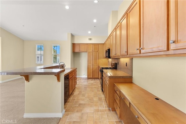 kitchen with a kitchen breakfast bar, backsplash, a sink, baseboards, and black appliances