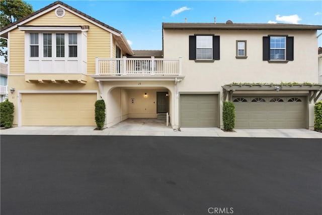 view of front of house with stucco siding, aphalt driveway, a balcony, and a garage