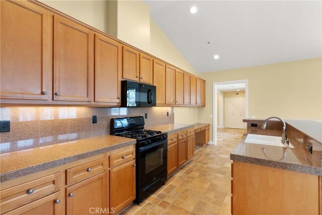 kitchen with a sink, tasteful backsplash, vaulted ceiling, stone finish flooring, and black appliances