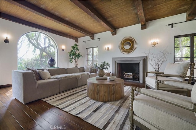 living room with a fireplace, hardwood / wood-style floors, a wealth of natural light, and beamed ceiling