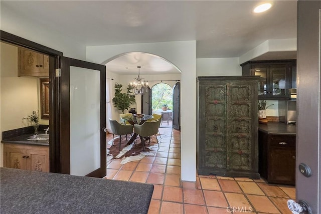 interior space featuring arched walkways, an inviting chandelier, light tile patterned floors, and a sink