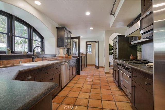 kitchen with recessed lighting, dark countertops, high quality appliances, and a sink