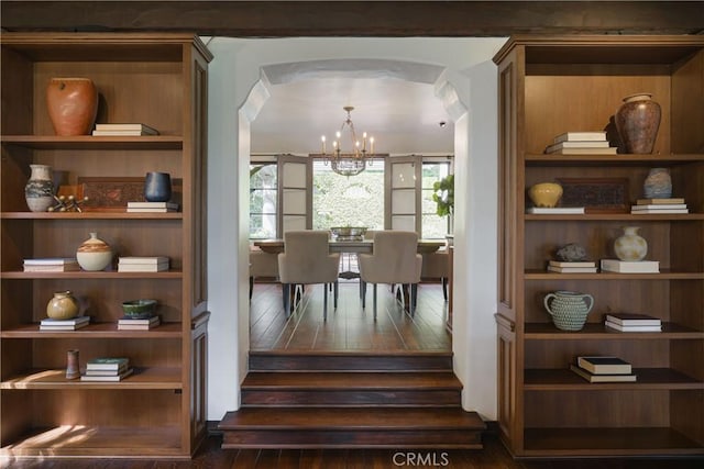interior space with arched walkways, hardwood / wood-style flooring, and an inviting chandelier