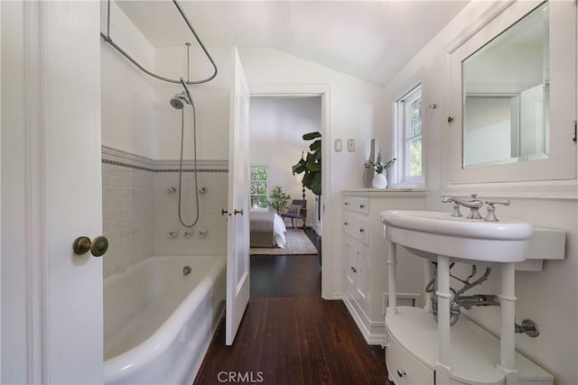 ensuite bathroom with vaulted ceiling, wood finished floors, shower / bathtub combination, and ensuite bathroom
