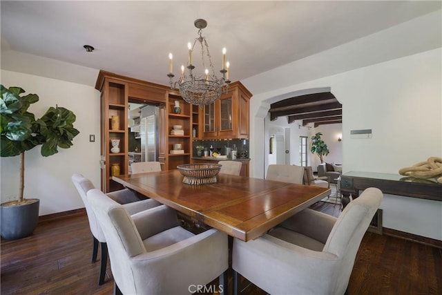 dining area featuring dark wood finished floors, arched walkways, beam ceiling, baseboards, and a notable chandelier