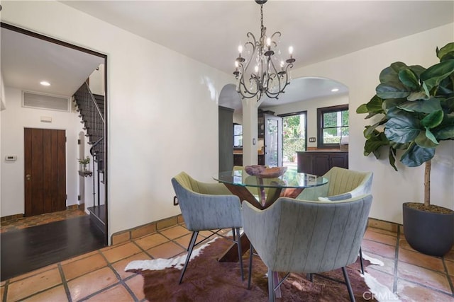 dining area with an inviting chandelier, visible vents, arched walkways, and stairs