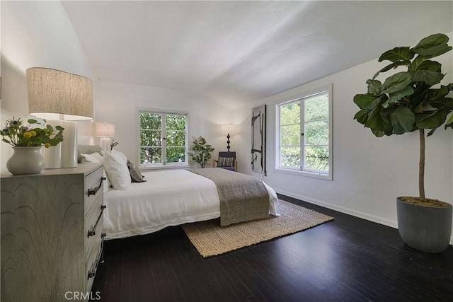 bedroom with vaulted ceiling, baseboards, dark wood-type flooring, and multiple windows