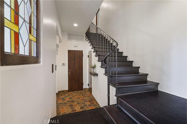 stairway featuring recessed lighting, arched walkways, and visible vents