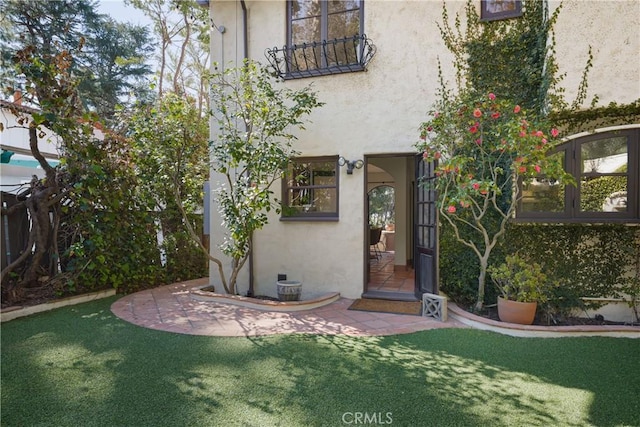 doorway to property featuring a lawn and stucco siding