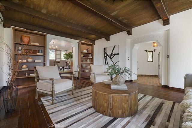 living area with arched walkways, a notable chandelier, beamed ceiling, wood finished floors, and wooden ceiling