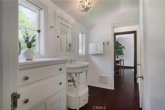 half bathroom with plenty of natural light, wood finished floors, visible vents, and vaulted ceiling