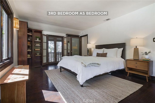 bedroom with wood finished floors, visible vents, access to exterior, and multiple windows
