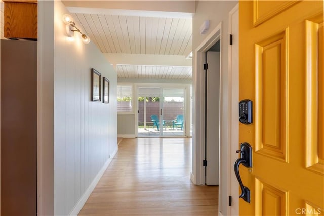 corridor featuring baseboards, light wood-style flooring, and wood ceiling