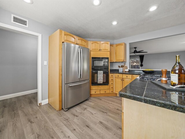 kitchen featuring recessed lighting, light wood finished floors, visible vents, tile countertops, and black appliances