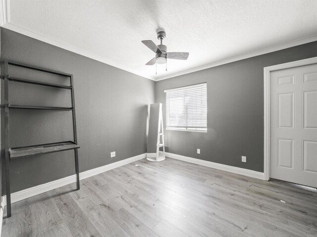 unfurnished bedroom featuring wood finished floors, a textured ceiling, ceiling fan, baseboards, and ornamental molding