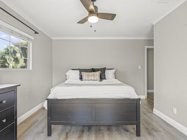 bedroom featuring light wood finished floors, baseboards, and crown molding