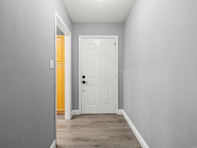 corridor with baseboards and wood finished floors