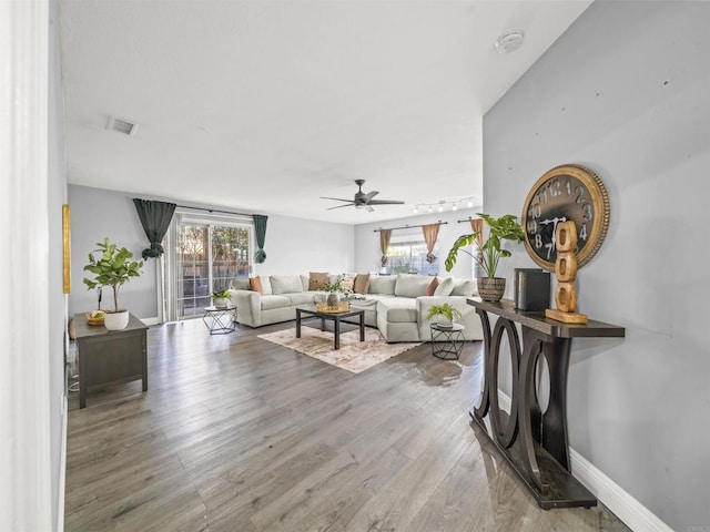 living area featuring visible vents, baseboards, a ceiling fan, and wood finished floors