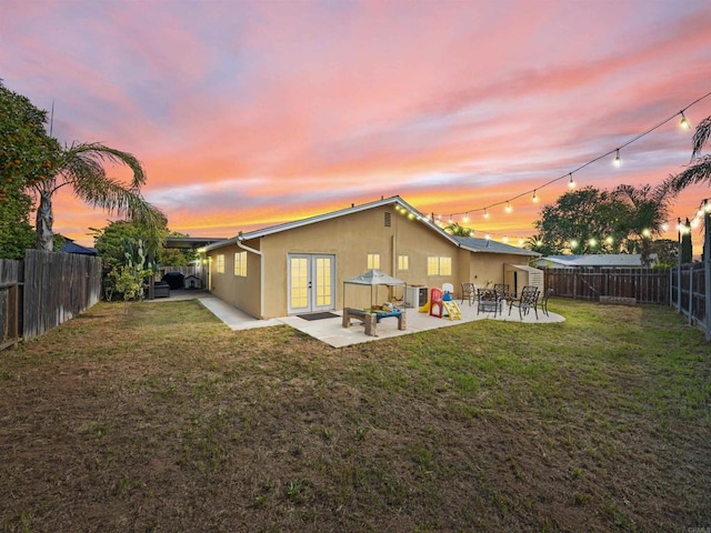 rear view of house featuring a yard, french doors, a patio area, and a fenced backyard