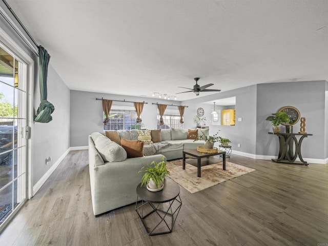 living area with baseboards, a ceiling fan, and wood finished floors