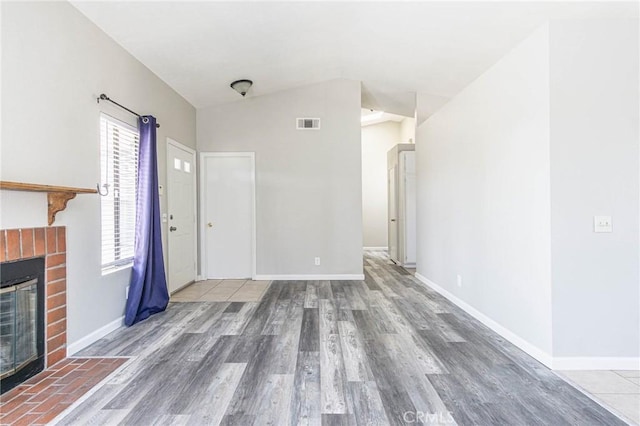 14292 Pinewood Dr, Hesperia, CA 92344 - unfurnished living room with vaulted ceiling, wood finished floors, visible vents, baseboards, and a brick fireplace