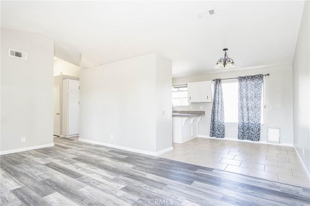 14292 Pinewood Dr, Hesperia, CA 92344 - unfurnished living room featuring lofted ceiling, a notable chandelier, visible vents, and baseboards