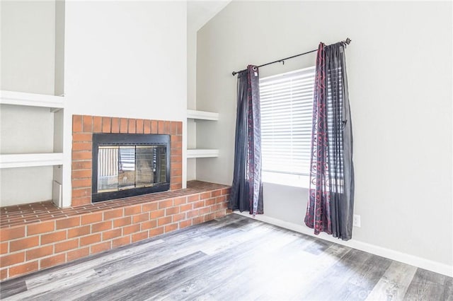 14292 Pinewood Dr, Hesperia, CA 92344 - unfurnished living room with wood finished floors, built in shelves, a wealth of natural light, baseboards, and a brick fireplace