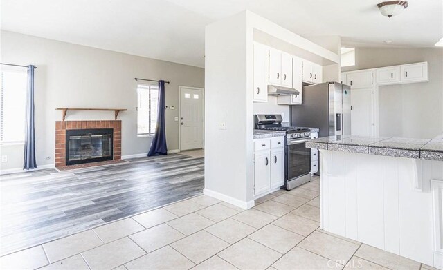14292 Pinewood Dr, Hesperia, CA 92344 - kitchen featuring tile counters, stainless steel appliances, white cabinets, lofted ceiling, and under cabinet range hood