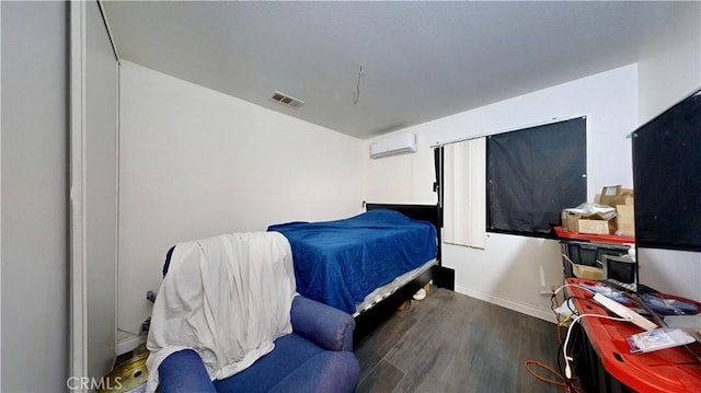 bedroom with an AC wall unit, baseboards, visible vents, and wood finished floors