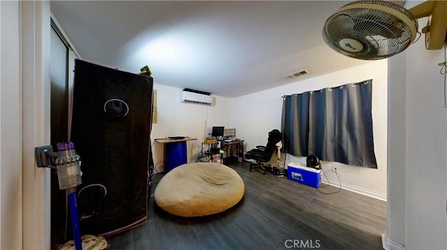 interior space with baseboards, visible vents, wood finished floors, and a wall mounted AC