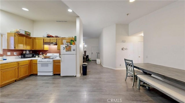 kitchen with light wood finished floors, white appliances, tile countertops, recessed lighting, and under cabinet range hood