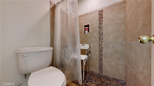 bathroom featuring toilet and a tile shower