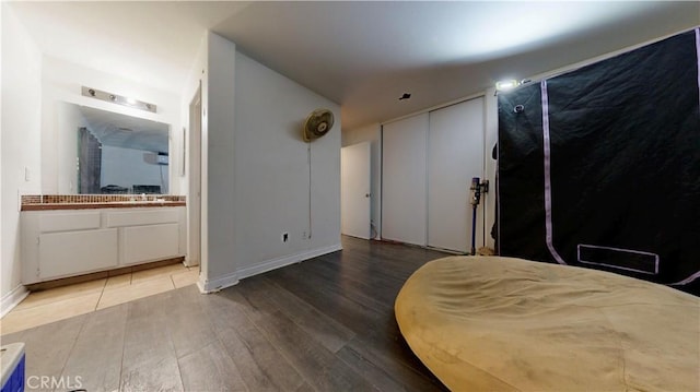bedroom featuring a sink, two closets, wood finished floors, and connected bathroom